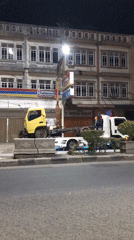 Two trucks partially block sidewalk in Lhokseumawe, Indonesia