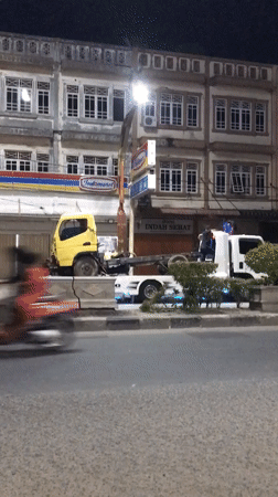 Two trucks partially block sidewalk in Lhokseumawe, Indonesia