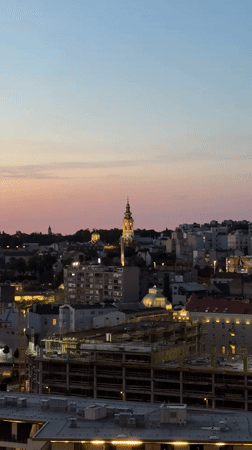 Belgrade sunset illuminates cathedral spire in evening cityscape