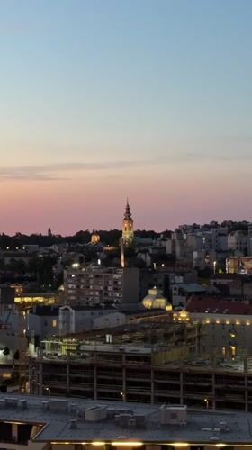 Belgrade sunset illuminates cathedral spire in evening cityscape
