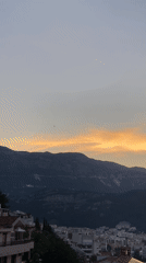Time-lapse sunset fades over a mountain-backed city