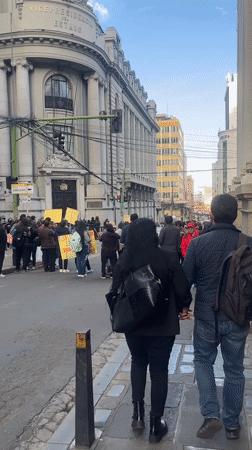 Daytime street protest with yellow signs in La Paz