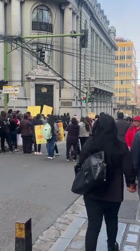Daytime street protest with yellow signs in La Paz