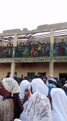Community gathering assembles in Akwanga, Nigeria near damaged building