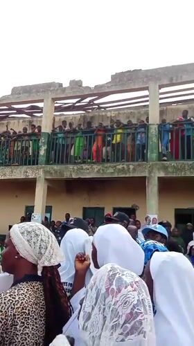 Community gathering assembles in Akwanga, Nigeria near damaged building