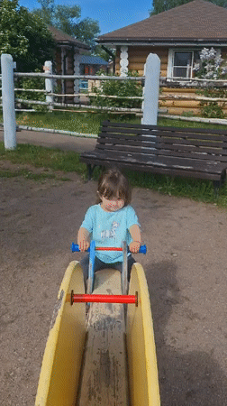 Toddler plays at Peterhof playground amid traditional Russian architecture