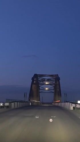 Driver records twilight bridge crossing in Chervlenoe, Russia