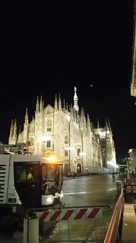 Night street sweeping in front of the illuminated Milan Duomo
