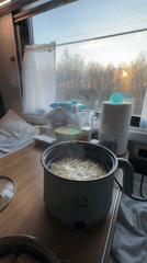 Passenger cooks with electric pot in Russian train compartment