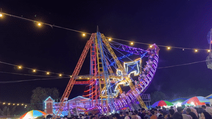 Night market bustles with seafood vendors, carnival rides