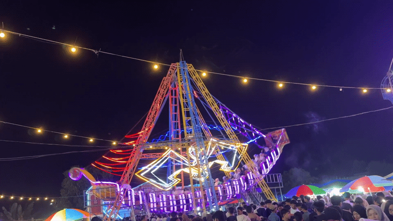 Night market bustles with seafood vendors, carnival rides