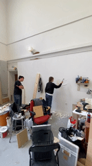 Men renovate Paris room, removing wallpaper and applying plaster