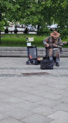 Street musician, construction work, pedestrians captured in city square