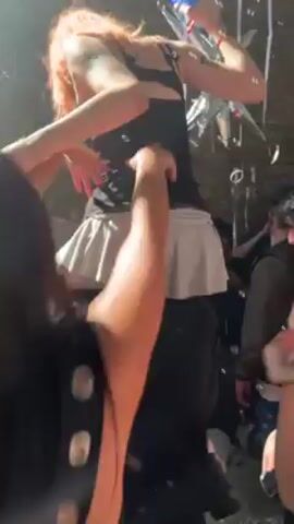 The video shows a group of young people dancing at a party. Bubbles are being blown into the air, and the lighting is dim with colored accents. Some people are smiling and enjoying themselves. There are balloons and streamers visible in the background. The crowd seems lively and energetic.