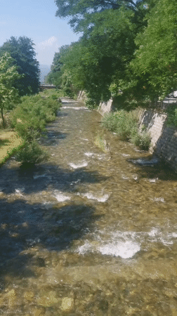 Clear river flows through Blagoevgrad under bright morning sky