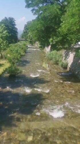 Clear river flows through Blagoevgrad under bright morning sky