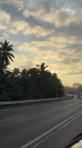 Motorcyclist crosses bridge at sunset in Tagum, Philippines