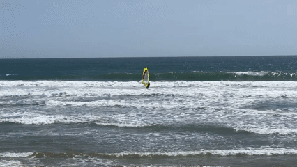 Windsurfer rides waves at Costa da Caparica beach Portugal