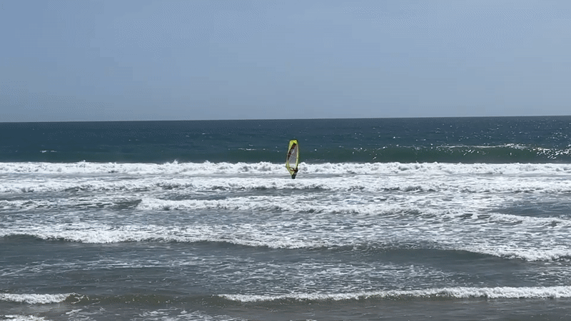 Windsurfer rides waves at Costa da Caparica beach Portugal