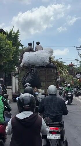 Waste collection truck with workers observed in Mengwi traffic