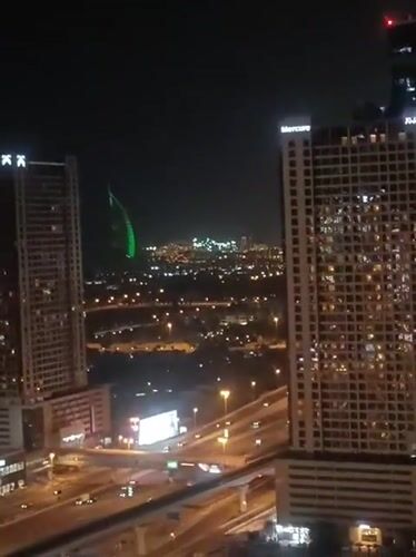 Dubai nighttime skyline captured with green-lit structure visible