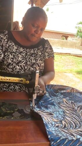 Woman operates sewing machine in outdoor workspace, Maigizo Nigeria