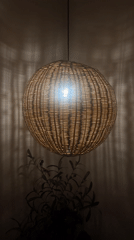 Woven pendant light glowing, casting patterned shadows on wall