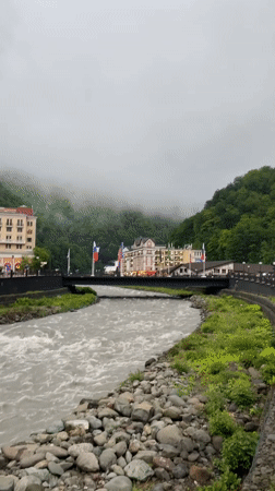 Fast-flowing river observed through misty mountain town Estosadok