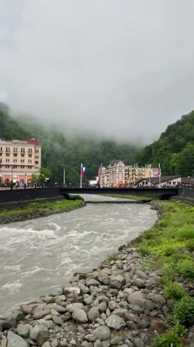 Fast-flowing river observed through misty mountain town Estosadok
