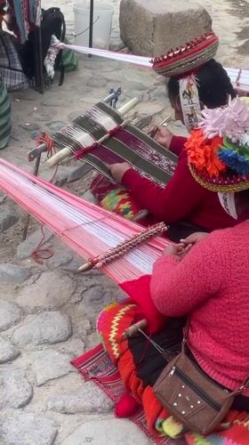 Indigenous women weave fabric on Ollantaytambo sidewalk