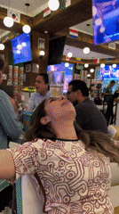 Woman performs glass balancing trick at flag-decorated Puebla restaurant