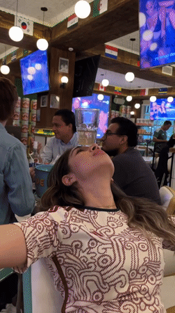 Woman performs glass balancing trick at flag-decorated Puebla restaurant