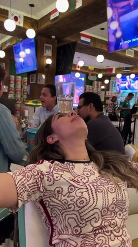 Woman performs glass balancing trick at flag-decorated Puebla restaurant