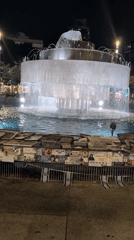 Dizengoff Fountain at night, flags and posters on surrounding barrier