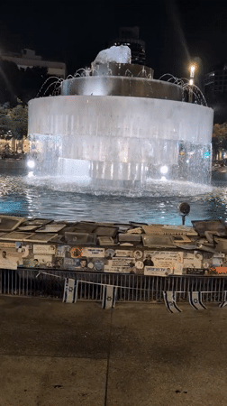 Dizengoff Fountain at night, flags and posters on surrounding barrier