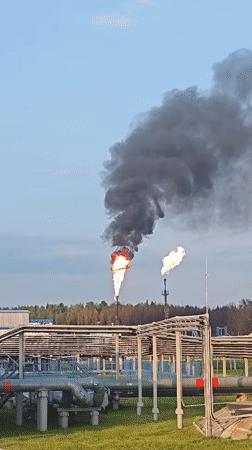 Twin industrial flares burn against a twilight sky