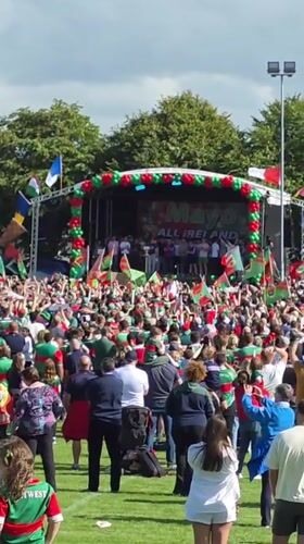 Green and red crowd rallies around a festive stage in Claremorris