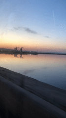 Sunset reflection captured over industrial waterway in Chaikovsky, Russia