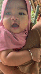 Baby in pink hijab held close in Kruengmate, Indonesia