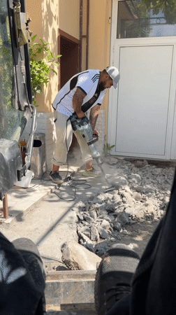 Construction worker jackhammers concrete walkway in Targovishte, Bulgaria