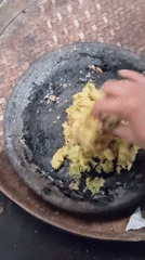 Woman prepares traditional food in stone mortar in Baron, Indonesia