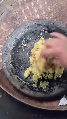 Woman prepares traditional food in stone mortar in Baron, Indonesia