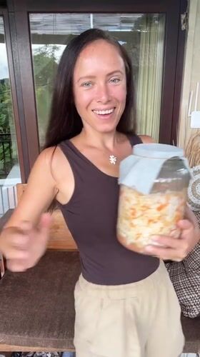 Woman displays fermented vegetables in jar in Ubud