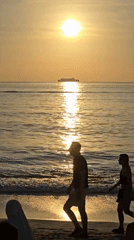 Horseback rider enjoys sunset beach ride as ship passes