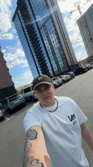 Man films selfie video in parking lot near tall buildings