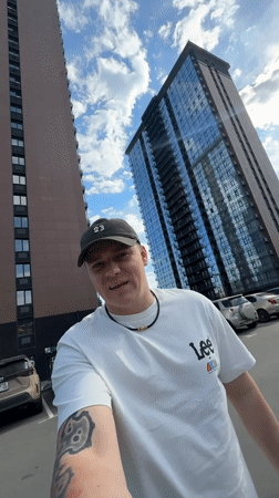 Man films selfie video in parking lot near tall buildings