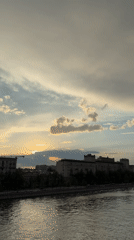 Witness captures sunset river cityscape with bridge and pedestrians