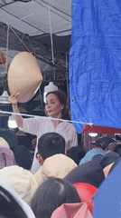 Woman displays traditional hat at Da Lat outdoor market