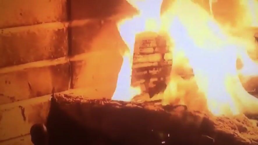 Man watches virtual fireplace on TV in Nigerian home