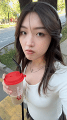 Drink in hand, headphones on, sidewalk scene in Almaty